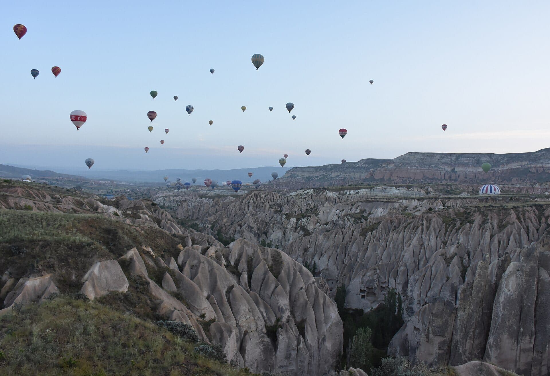 Balony na ogrzane powietrze o świcie nad skalnymi dolinami w okolicach Göreme